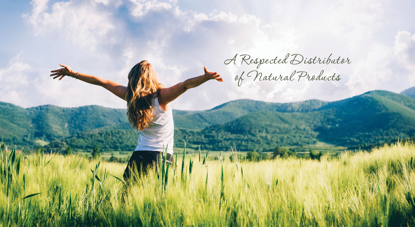 A woman reaching her arms out to the sky while standing in a field of grass