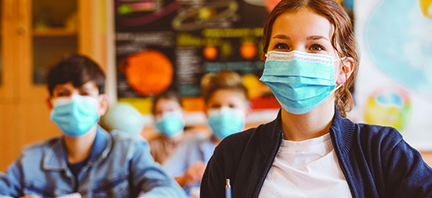 High school students at school, wearing N95 Face masks. Teenage girl sitting at the school desk and listening to the teacher.