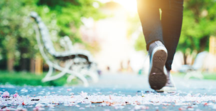 A person running on a park path on a sunny summer day