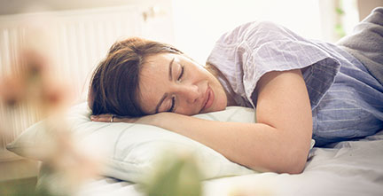 A woman peacefully napping on a bed.