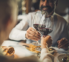 Two people at dinner clinking their wine glasses