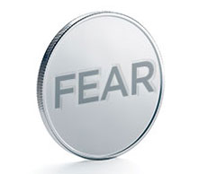 A coin standing on edge with the word FEAR embossed on it