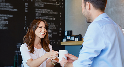 Young barista serving coffee to male customer in cafe