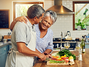 Two elderly people cooking together in a home kitchen