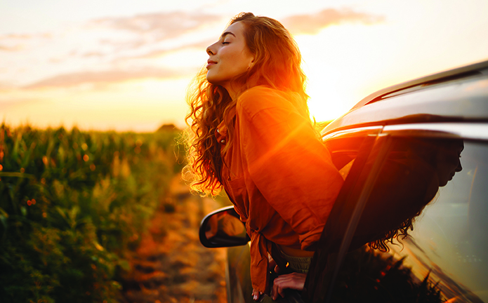 A woman sticks her upper body out of the window of a car.